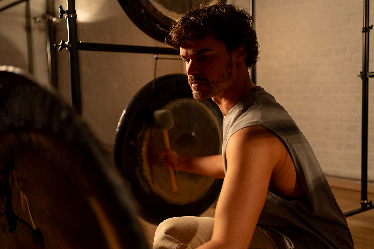 Sound healer playing a large gong, illustrating the power of vibration and music in the session