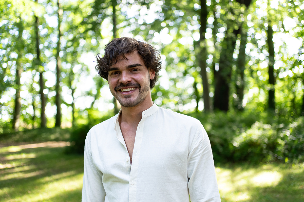 Smiling man standing in a sunlit forest, symbolizing the discovery of true self and safety in nature