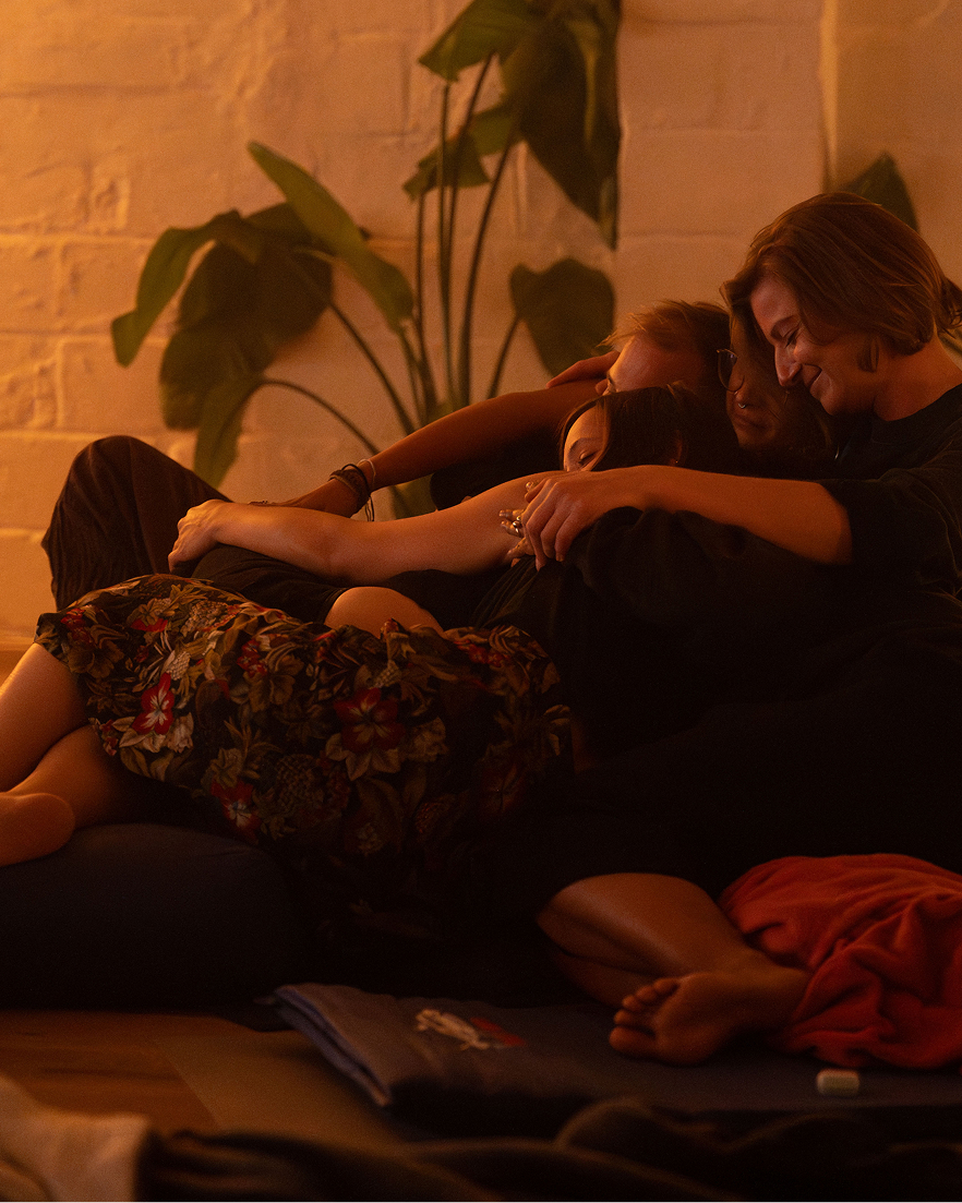 Relaxation and meditation: a woman relaxes on a mat in a sound therapy studio with lit candles, large gongs, and crystal singing bowls.
